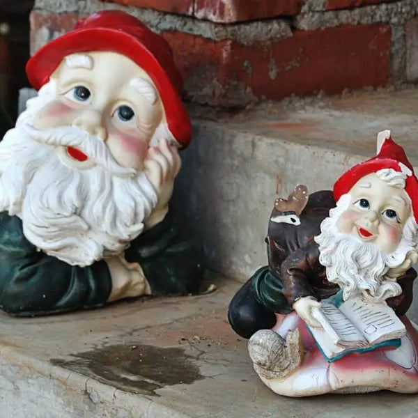 Deux nains de jardin au bonnet rouge souriants allongés sur un escalier